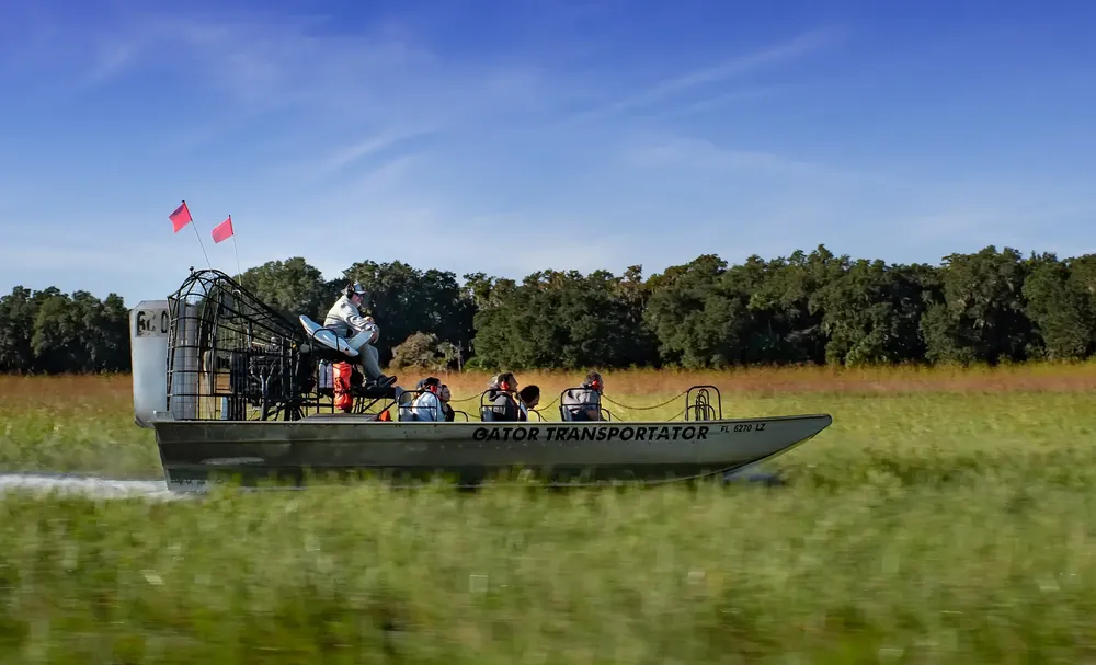 Airboat crossing open Florida marsh under a blue sky